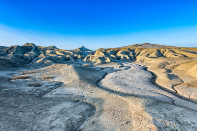 Scenic view of arid landscape against clear blue sky