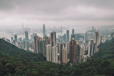 High angle view of modern buildings in city against cloudy sky