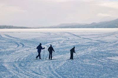 People on field by snowcapped mountain against sky