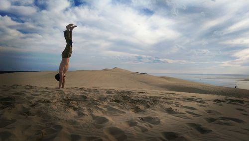 Scenic view of man doing a handstand on the beach