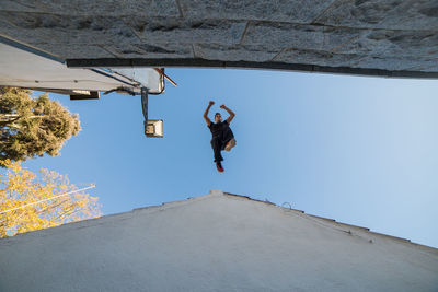 Low angle view of man jumping on rooftop