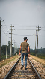 Rear view of man walking on railroad track