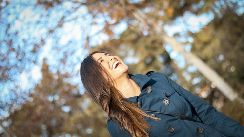 Low angle view of young woman against tree