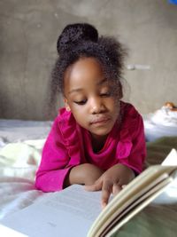 Girl looking away while sitting on book