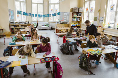 Male and female students studying together while sitting at desk in classroom