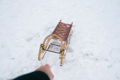 Cropped hand of person pulling sled on snow