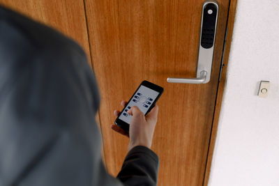 High angle view of girl with mobile phone unlocking door