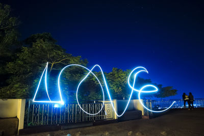 Light trails against blue sky at night