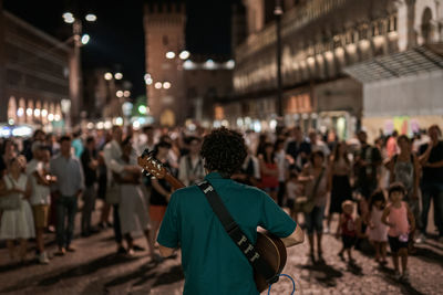 Rear view of people on street in city at night