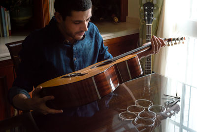 Young man playing guitar at home