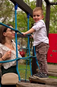 Mother holding her little toddler on playground ladder