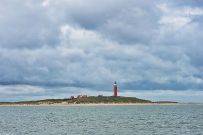 Lighthouse by sea against sky