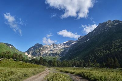 Scenic view of road by mountains against sky