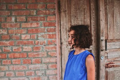 Side view of woman standing against brick wall