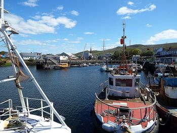 Sailboats moored at harbor against buildings in city