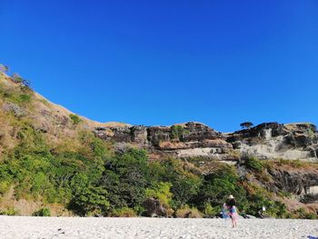 Woman standing on mountain against clear blue sky