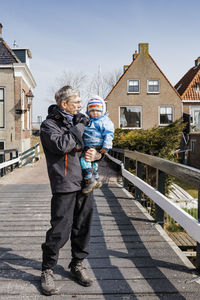 Full length of grandfather with grandchild standing outdoors