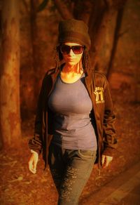 Portrait of woman wearing sunglasses while walking in forest