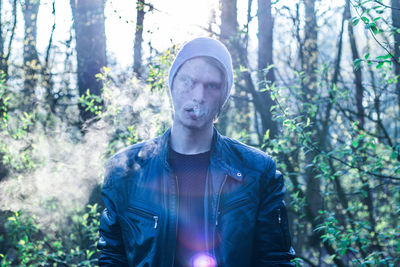 Portrait of man smoking cigarette in forest