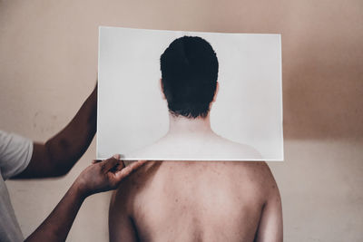 Rear view of shirtless man standing in bathroom