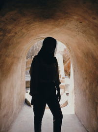 Rear view of man and woman standing in tunnel