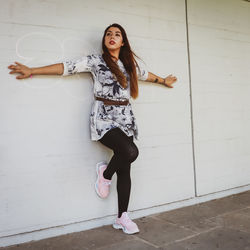 Portrait of young woman standing against wall