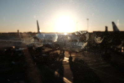 Close-up of wet windshield against sky during sunset