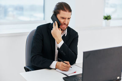 Mid adult man using mobile phone while sitting on table