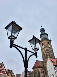 Low angle view of street light by building against sky