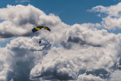 Low angle view of person paragliding against cloudy sky