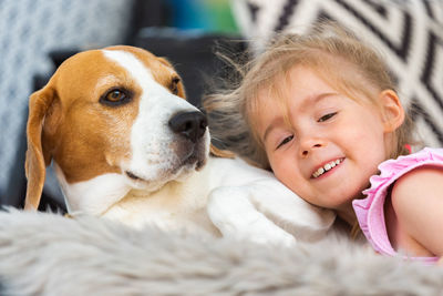 Child cuddle a dog on backyard sofa.