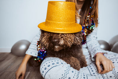 Midsection of woman holding hat while sitting with dog at home