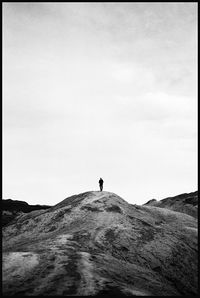 Rear view of man standing on sand against sky