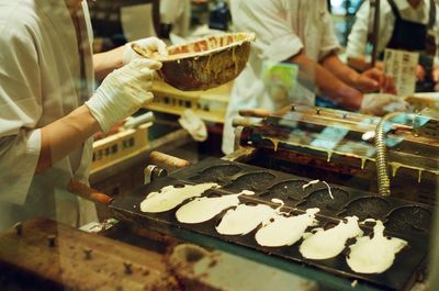 Mid section of chefs preparing food seen through glass