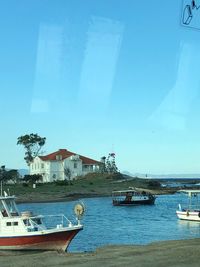 Sailboats moored on sea against buildings in city