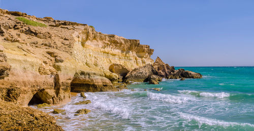 Scenic view of rocks in sea against clear sky