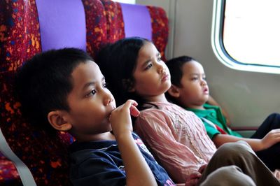 Siblings looking away while traveling in train