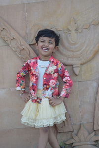 Portrait of a smiling girl standing against wall