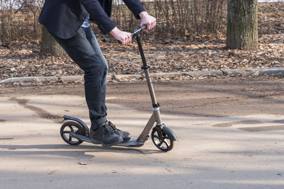 Low section of man riding push scooter