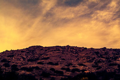 Scenic view of cliff against sky at sunset