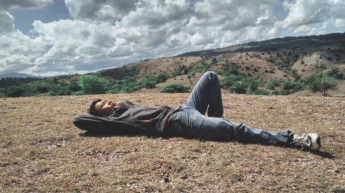 Man lying on field against sky