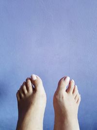 Low section of woman against blue wall