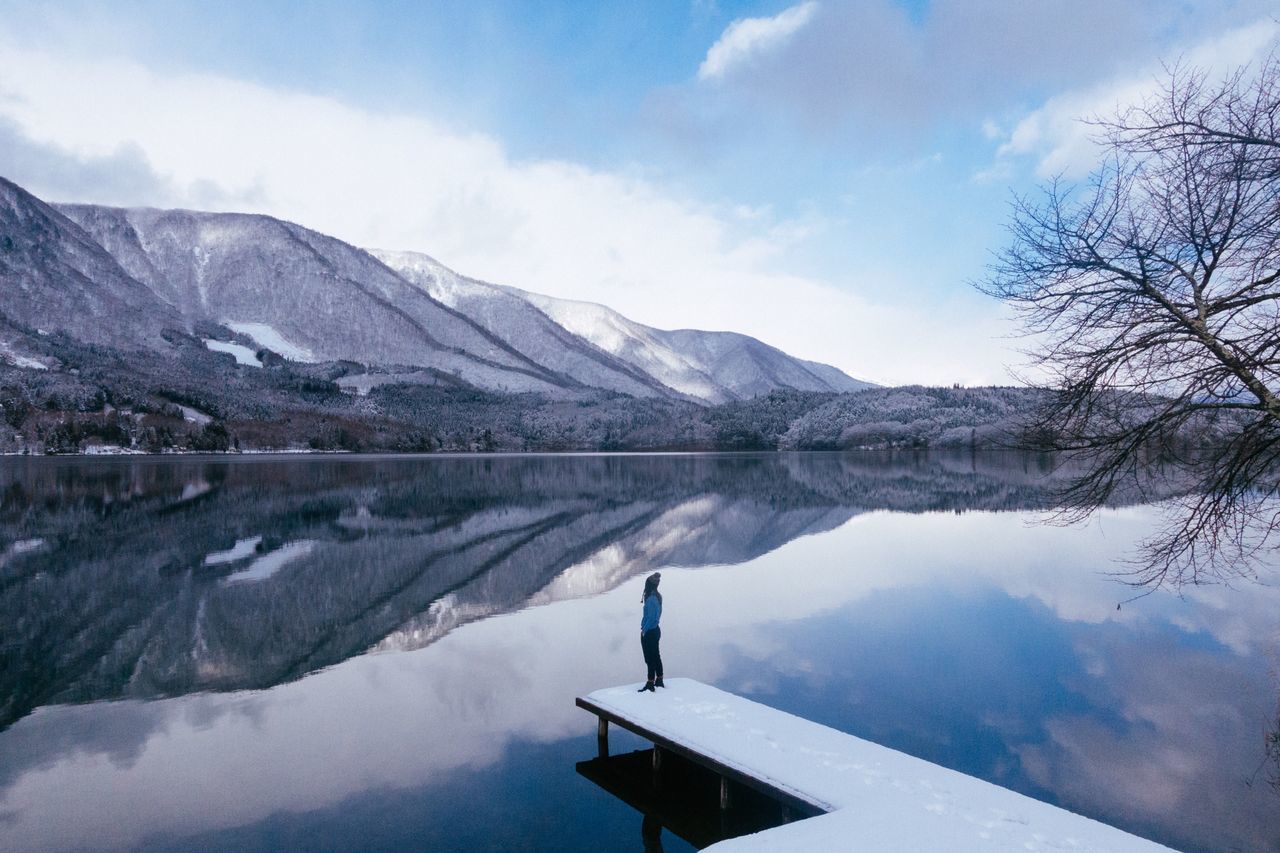 mountain, snow, beauty in nature, lake, nature, reflection, scenics, water, sky, mountain range, tranquility, tranquil scene, cold temperature, waterfront, outdoors, winter, day, snowcapped mountain, one person, tree, people