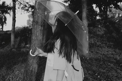 Side view of teenage girl holding umbrella on land