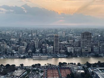 Aerial view of buildings in city against sky during sunset