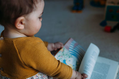 Boy sitting on book at home