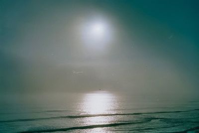 Scenic view of sea against bright sun