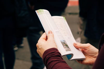 Cropped hands of female tourist reading book outdoors