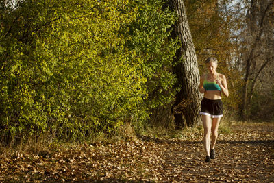 Woman jogging on field by forest