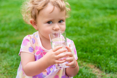 Portrait of cute baby girl sitting on field